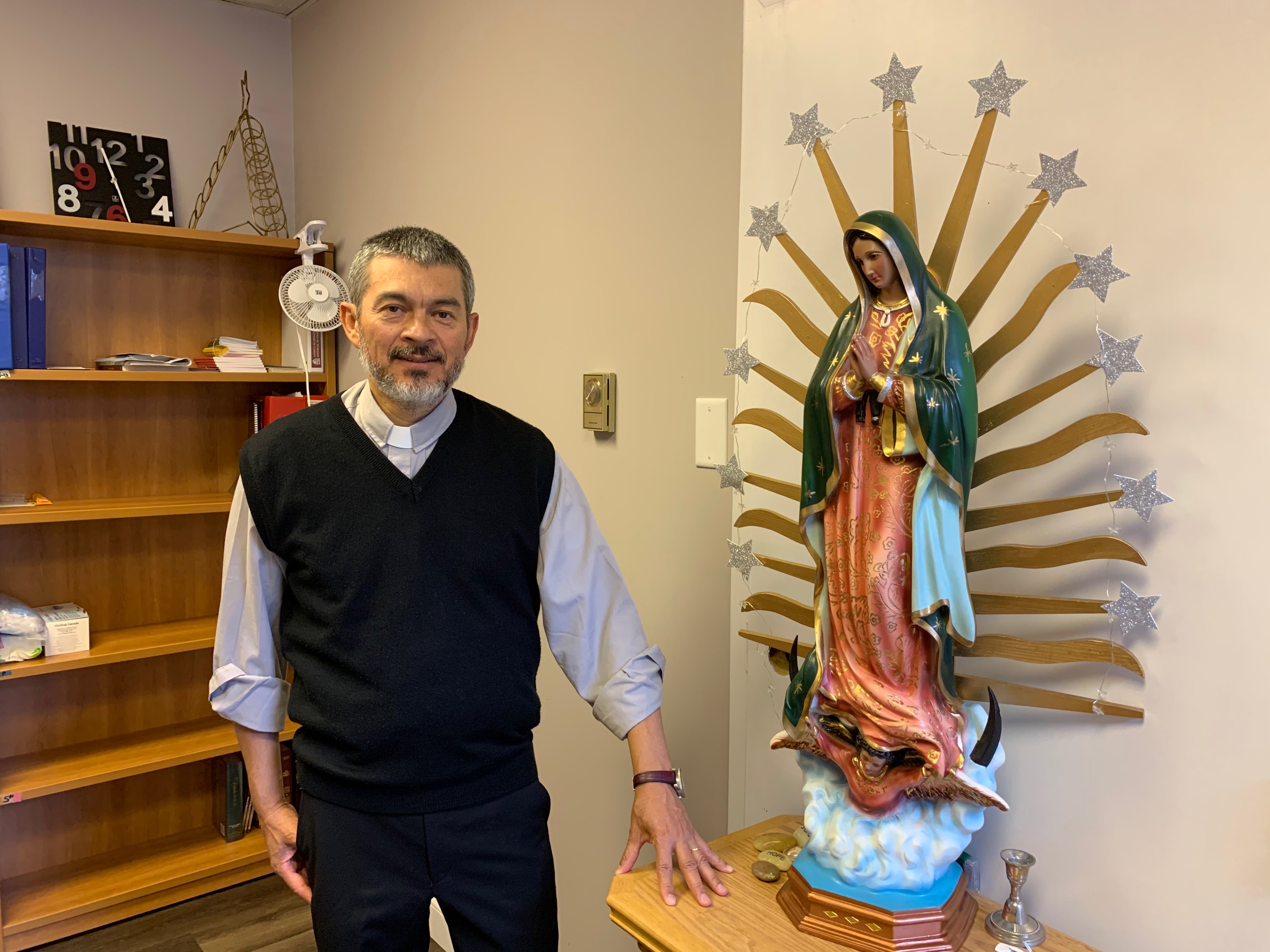 Fr Feliciano standing besides statue of our Lady
